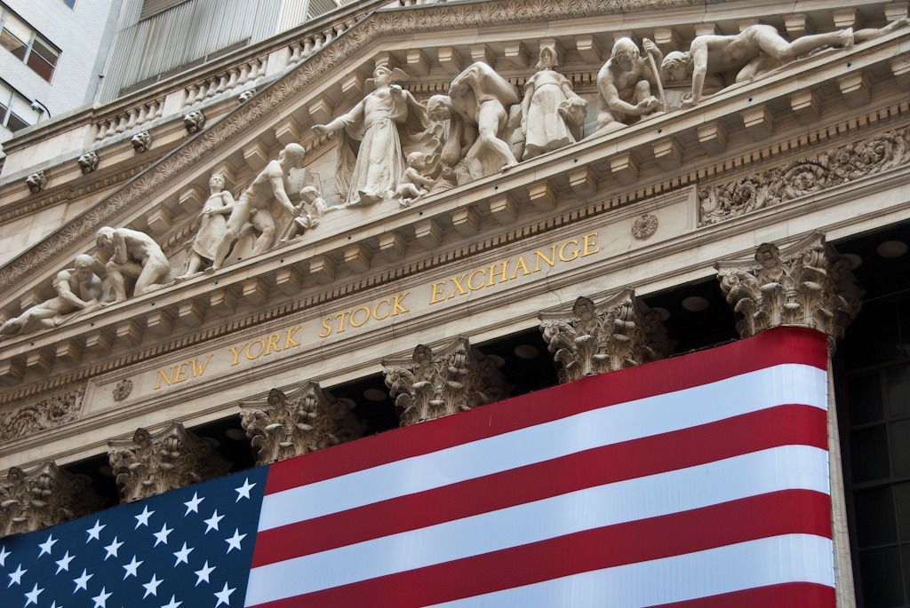 The facade of the New York Stock Exchange with the flag of the US in front of it